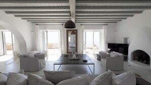 A spacious living room with a high ceiling, a central table, and seating areas. - Villa Prive 88 Mykonos (Mykonos)