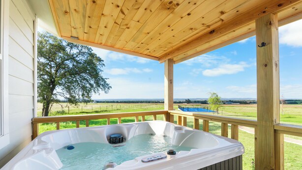 Un jacuzzi en una terraza de madera con vistas a un paisaje verde.