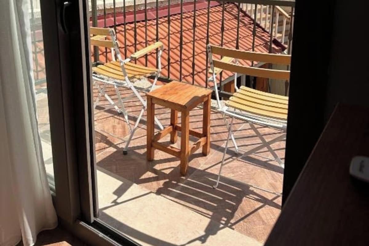 A balcony with a red-tiled floor, a wooden chair, and a small table.