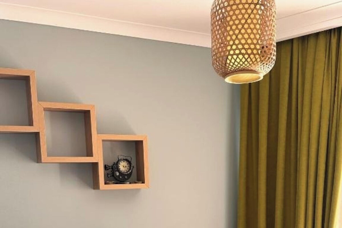 Un dormitorio con una cama, una repisa en la pared con un reloj y una lámpara colgante.