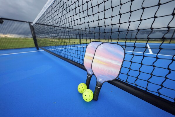 Una cancha de tenis con una red, dos raquetas y dos pelotas.