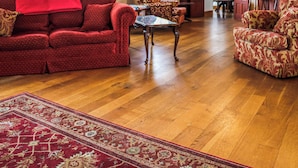 A living room with a red sofa, patterned armchairs, a wooden coffee table, and a red patterned rug. - 6 bedroom accommodation in Narbeth (Narbeth)