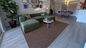 Un salon moderne comprenant un canapé d’angle, une table basse et un coin repas avec une table et des chaises.