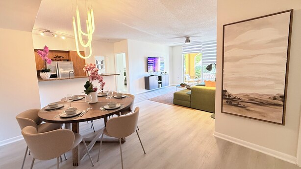 Un espace repas moderne avec une table ronde, six chaises et un luminaire suspendu au plafond.