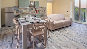 A modern kitchen with a dining area, a sofa, and a view of the outdoors. - Katia House - Lavender Apartment (Castelnuovo Calcea)