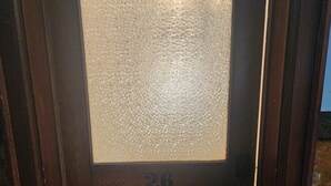 A wooden door with a frosted glass panel and the number 26.
