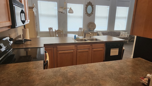 A kitchen with a central island, wooden cabinets, a dishwasher, and a stove.