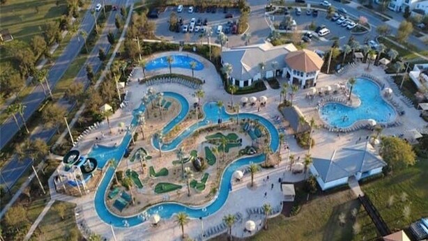 Vista aérea de un resort con múltiples piscinas, un edificio central y vegetación circundante.
