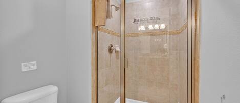 A modern bathroom with a glass-enclosed shower, a toilet, and a bathtub.