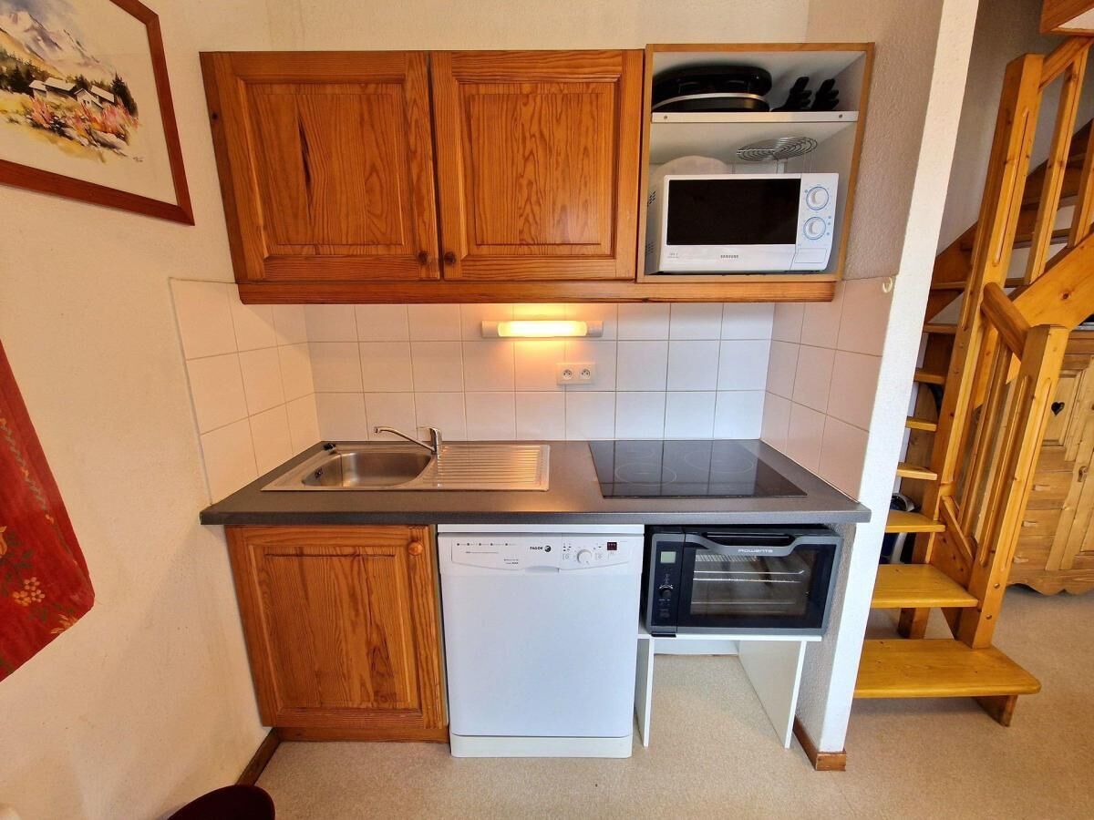 A compact kitchen with wooden cabinets, a microwave, a dishwasher, and a toaster.