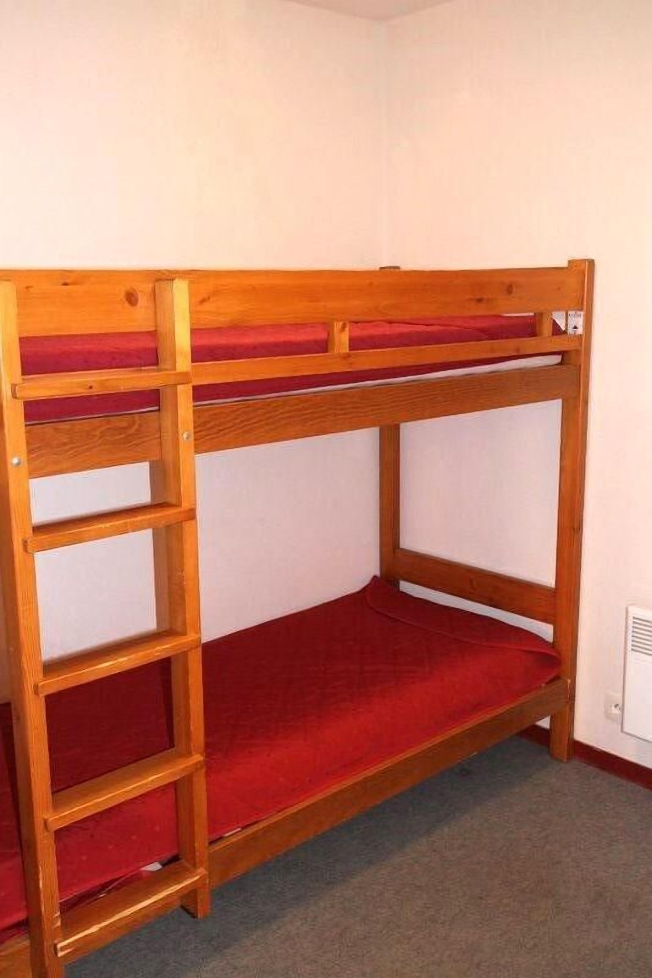 Un letto a castello con struttura in legno e biancheria rossa.