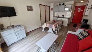 Um espaço compacto para viver, com cozinha compacta, área de refeições e sofá vermelho.