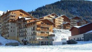 Un conjunto de edificios de madera de varios pisos con balcones, frente a una montaña nevada.