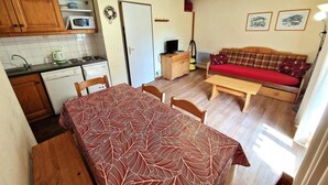 Una cocina compacta con armarios de madera, un microondas y una mesa de comedor con mantel estampado.