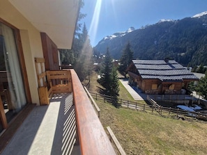A balcony with a view of a mountain and a wooden building with a sloped roof.