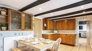 Uma cozinha moderna com armários de madeira, uma mesa de jantar para quatro pessoas e um banco.