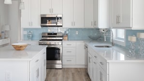 Una cocina moderna con armarios blancos, electrodomésticos de acero inoxidable y un salpicadero azul.