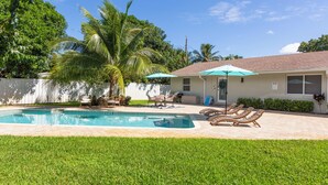 A residential backyard with a swimming pool, lounge chairs, and a covered patio area. - Near Beach/Downtown. Private Backyard. Pack n Play (Delray Beach)