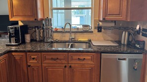 A kitchen with wooden cabinets, a stainless steel coffee maker, a sink, and a dishwasher.