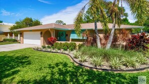 A single-story house with a garage, surrounded by well-maintained landscaping and a palm tree.