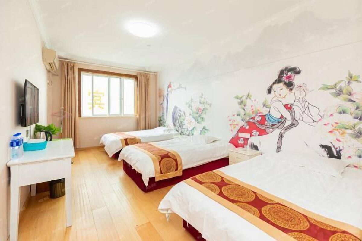 A hotel room with two beds, a desk, a TV, and a window with curtains.