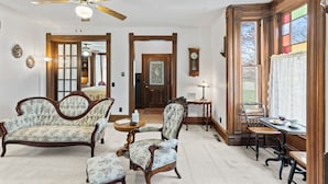 A traditional living room with a sofa, armchairs, a dining table, and a ceiling fan. - Historic 1890, 3-bed Victorian townhome in welcoming Monett with WiFi, AC (Monett)