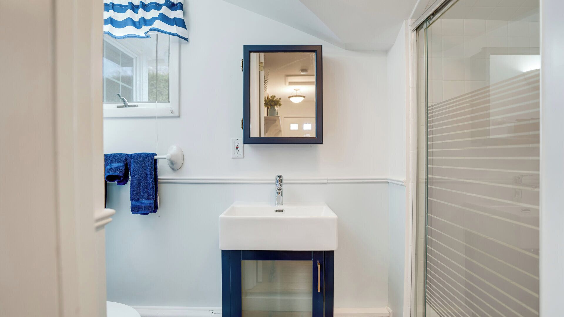 Un baño con un lavabo blanco, un espejo y un perchero para toallas.