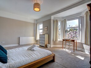 Een slaapkamer met een bed, een dressoir, een bureau en een radiator.