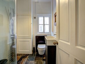 Een badkamer met een wit toilet, een raam en een wastafel.