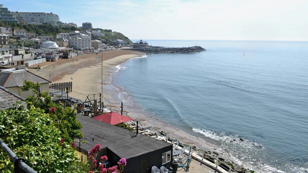 A coastal town with a beach, buildings, and a pier.