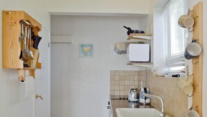A compact kitchen with a sink, countertop, and various utensils.