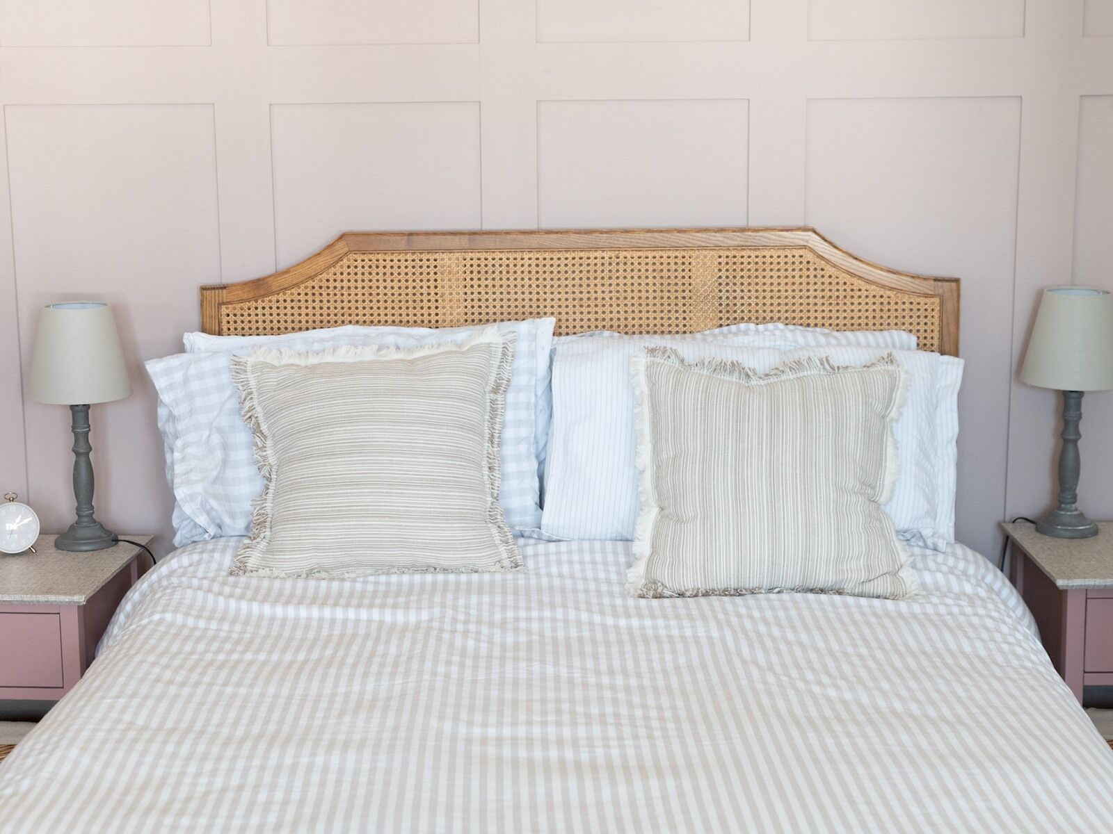 A bed with a checkered bedspread, two bedside lamps, and a wooden headboard.
