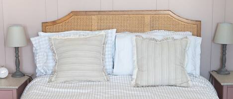 A bed with a checkered bedspread, two bedside lamps, and a wooden headboard.