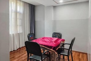 A small room with a wooden floor, a table with a red tablecloth, and two black chairs. - Mojiang XinXing Business Hotel (Mojiang)