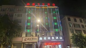 A building with multiple floors, a sign with Chinese characters, and a storefront with a phone number. - Mojiang XinXing Business Hotel (Mojiang)