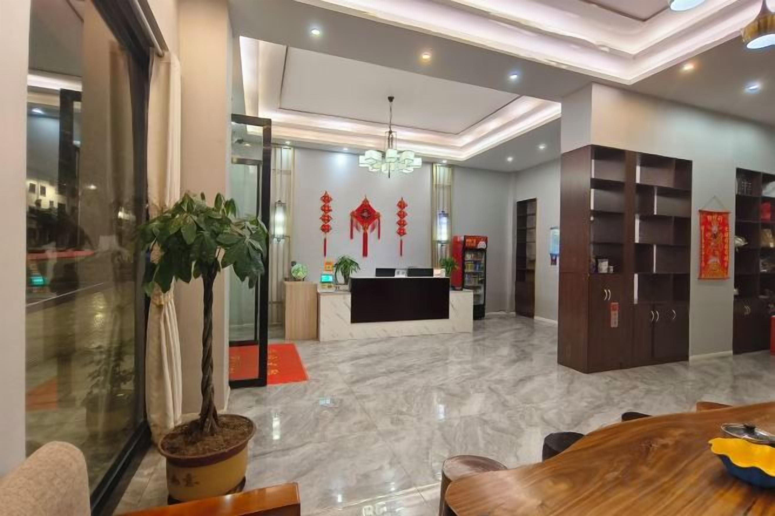 A hotel lobby with a reception desk, seating area, and a large potted plant.