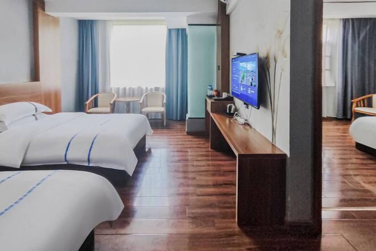 A hotel room with two beds, a TV, a desk, and a chair.