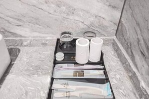 Een badkamer met een marmeren vloer, een dienblad met toiletartikelen en een handdoekhouder.