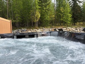 Un bain à remous entouré de rochers et d’arbres.