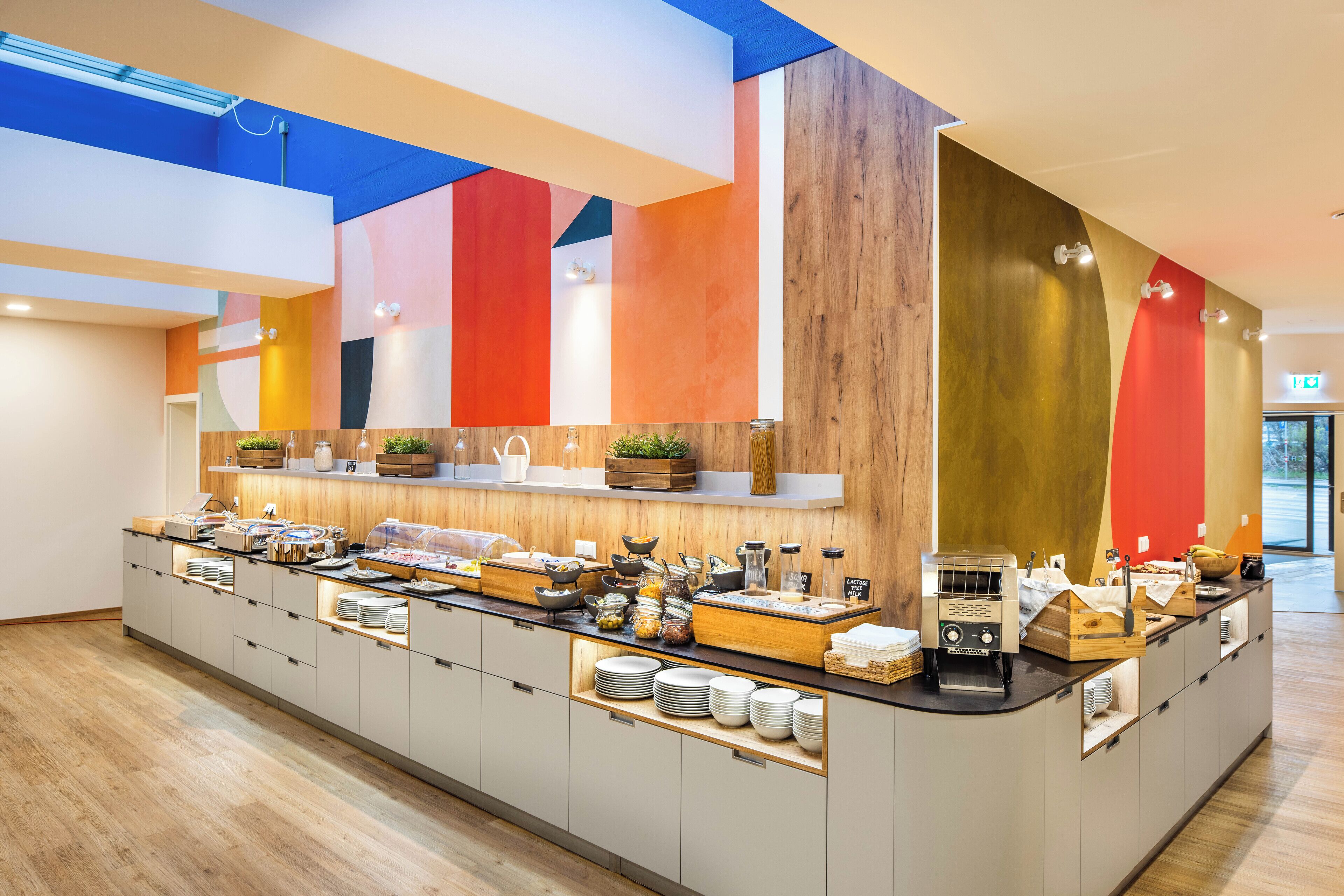 Una barra de desayuno moderna con diversas opciones de comida y una máquina de café.