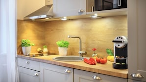 A modern kitchen with a stainless steel sink, wooden countertop, and built-in cabinets. - Jimmys Apartments XXL (Vienna)