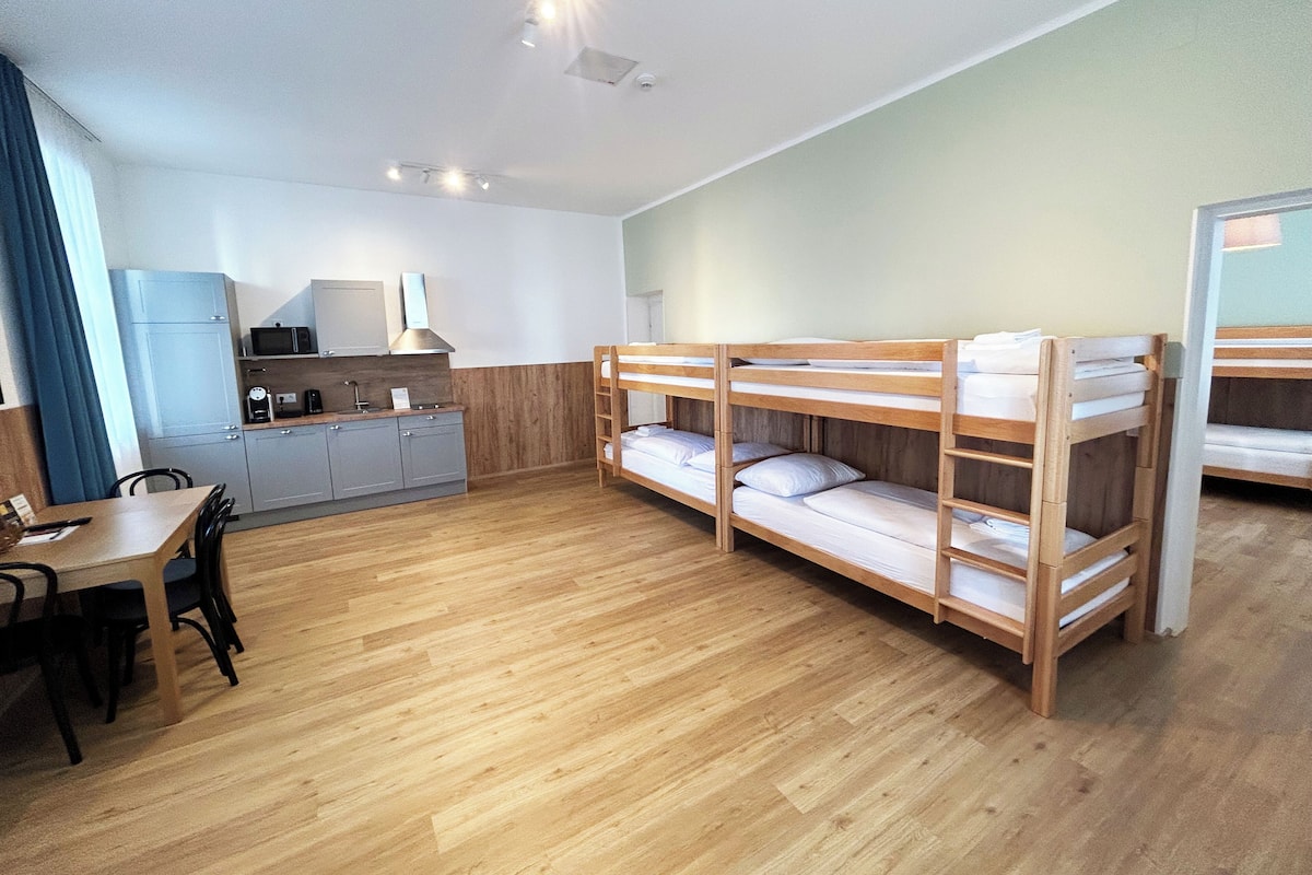 A compact room with bunk beds, a kitchenette, and a dining area.