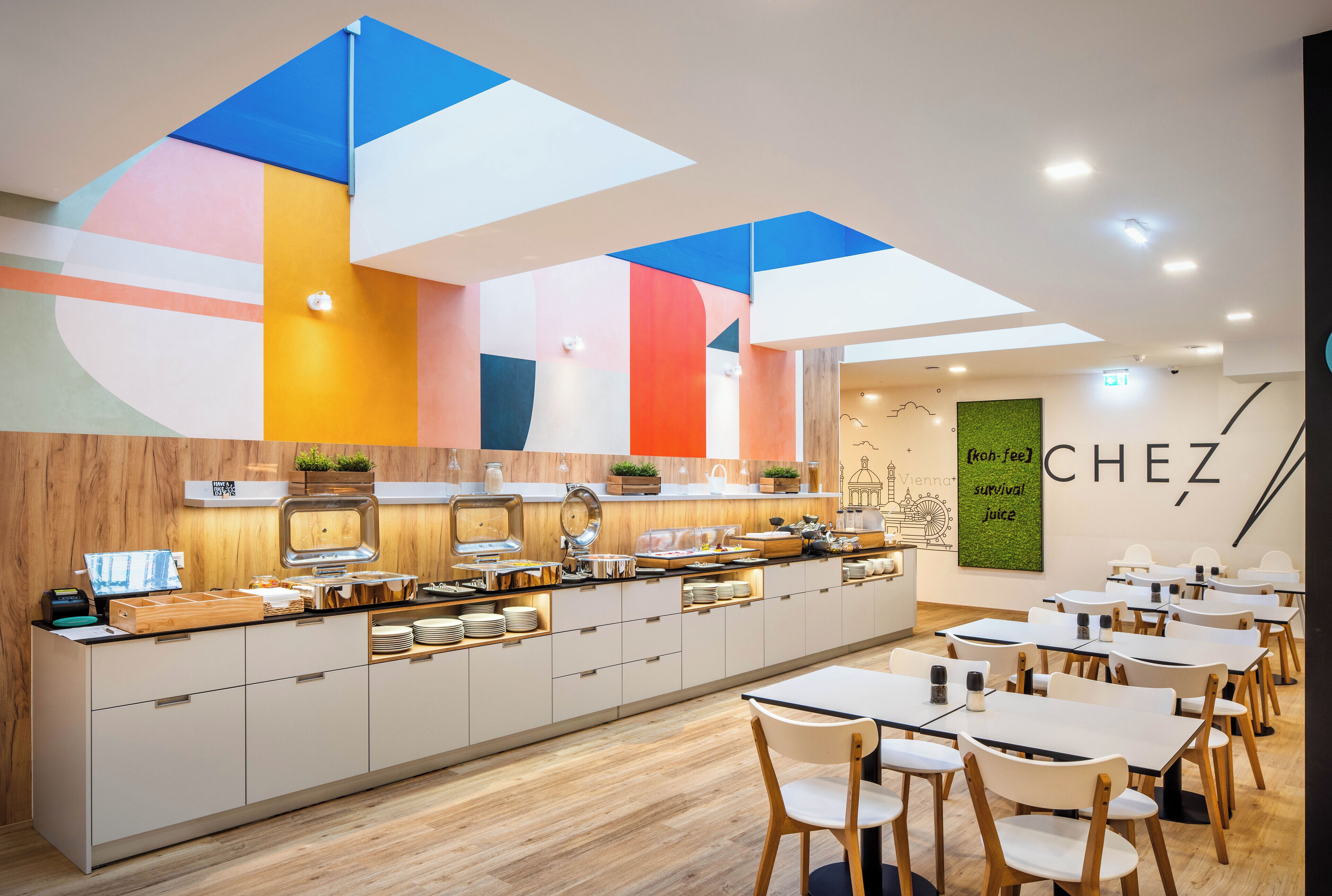 Un café moderne avec un long comptoir, des chaises blanches et un logo sur le mur.