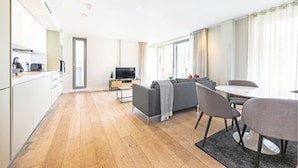 A modern living room with a sofa, chairs, a dining table, and a TV. - Accomodo London Southbank - Spacious & Elegant Apartments near Big Ben & London Eye (London)