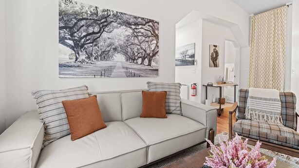 A living room with a sofa, a coffee table with flowers, a fireplace, and a painting on the wall.