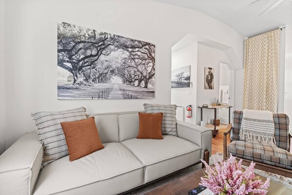A living room with a sofa, a coffee table, and a painting on the wall.