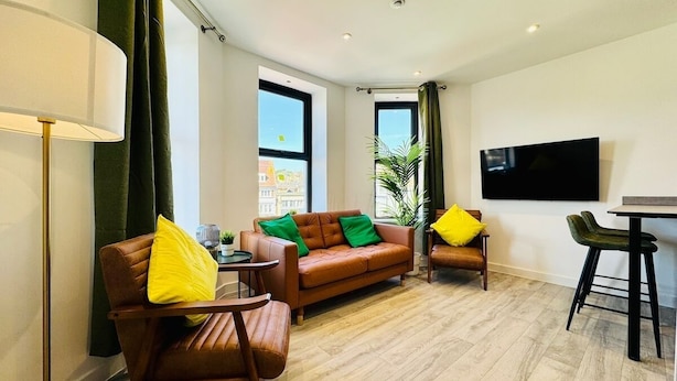 A modern living room with a sofa, armchairs, a dining table, and a TV. - Central Bournemouth | 2-Bed, 4 Guests | Prime Spot (Bournemouth, Christchurch and Poole)