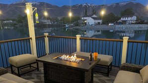 Une terrasse dotée d’un foyer, d’un espace salon et offrant une vue sur un lac et des montagnes.