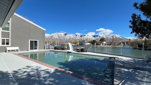 Une piscine avec vue sur des montagnes enneigées et un lac.