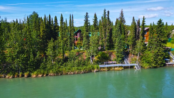 A lakeside lodge with cabins surrounded by dense forest, accessible by a wooden dock.